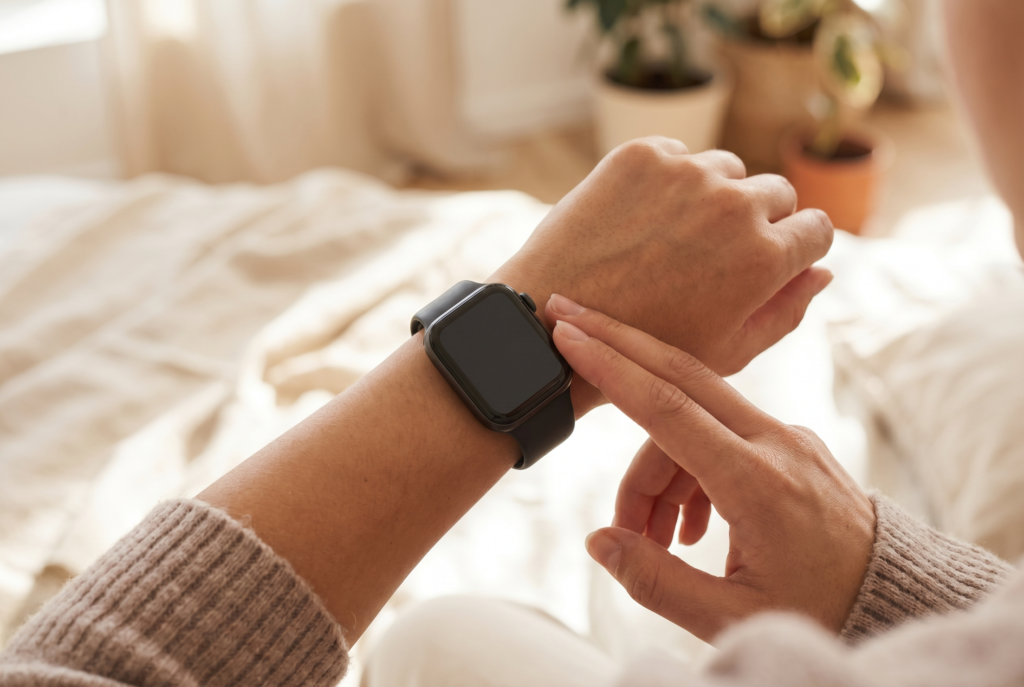 A wrist wearing a fitness watch with fingertips resting on the pulse point